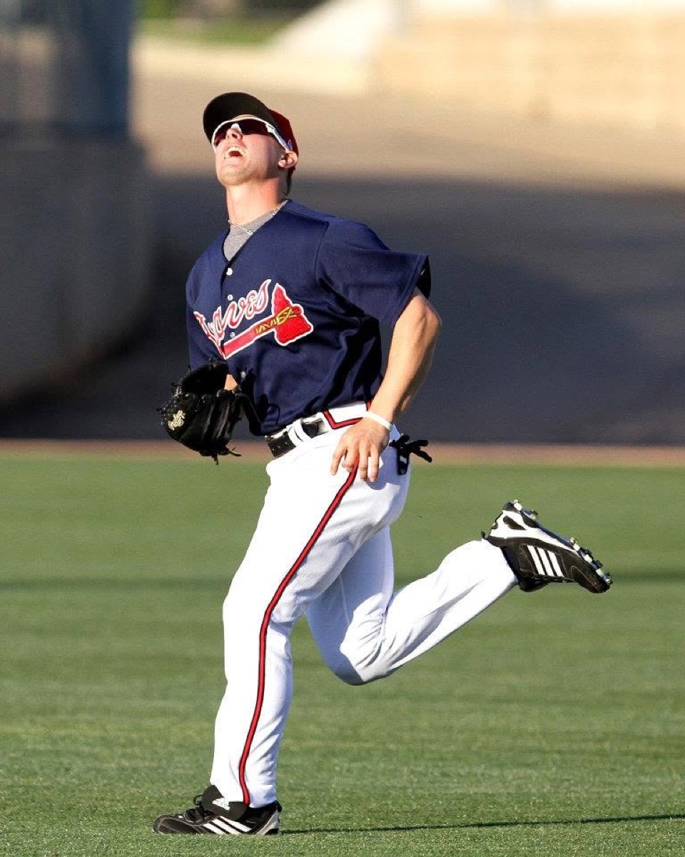 Cory Harrilchak tracking a fly ball in a navy Braves jersey